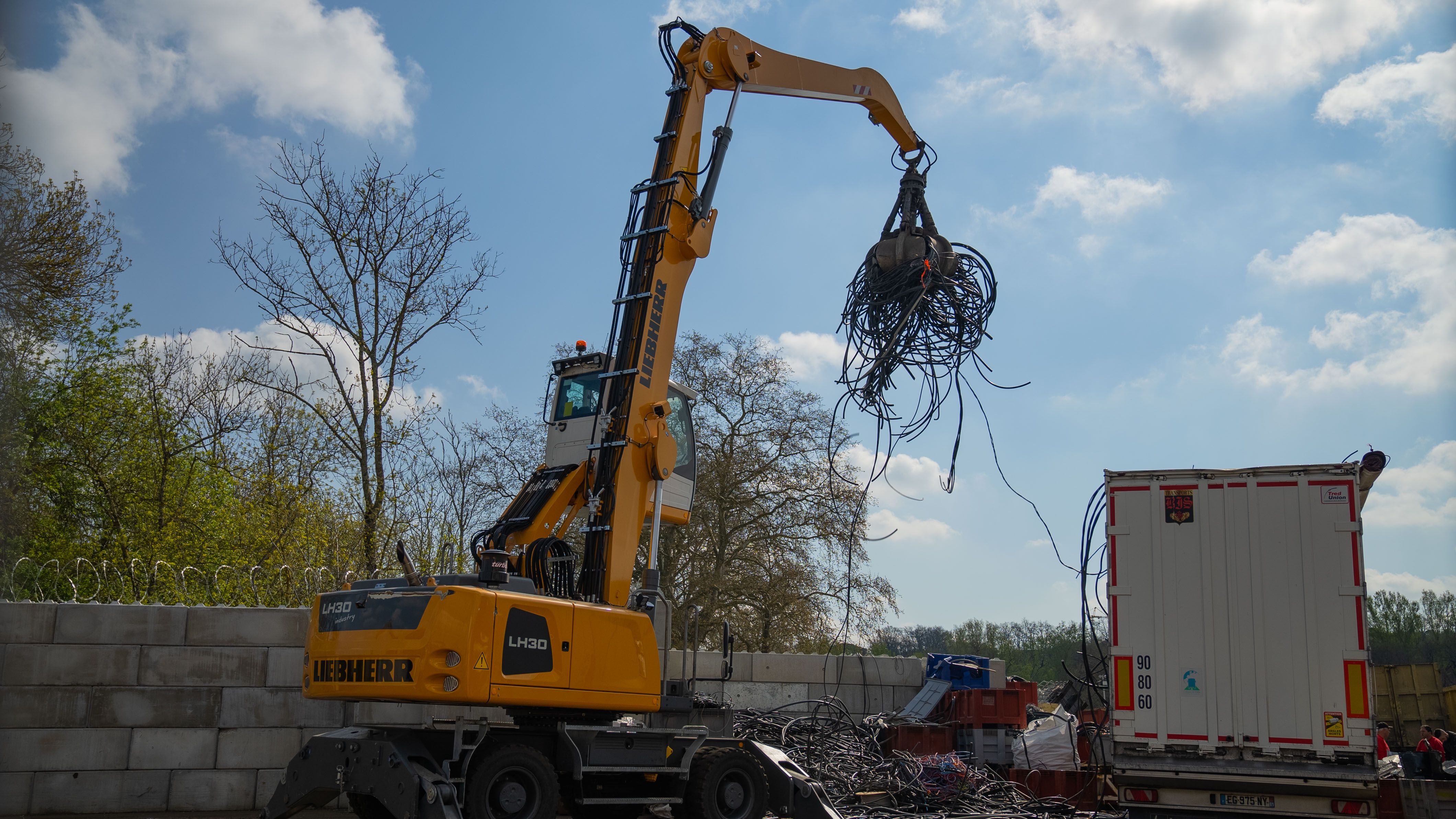 This picture shows a crane filling a skip with ferrous metals